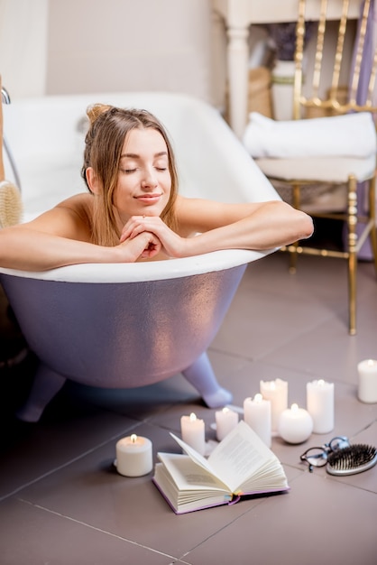 Portrait d'une belle femme allongée dans la baignoire rétro dans la salle de bain vintage