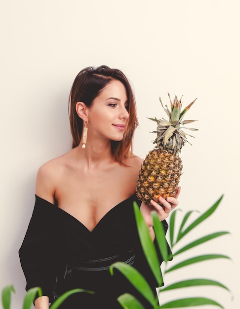 Portrait de belle femme avec ananas et branche de palmier sur fond blanc