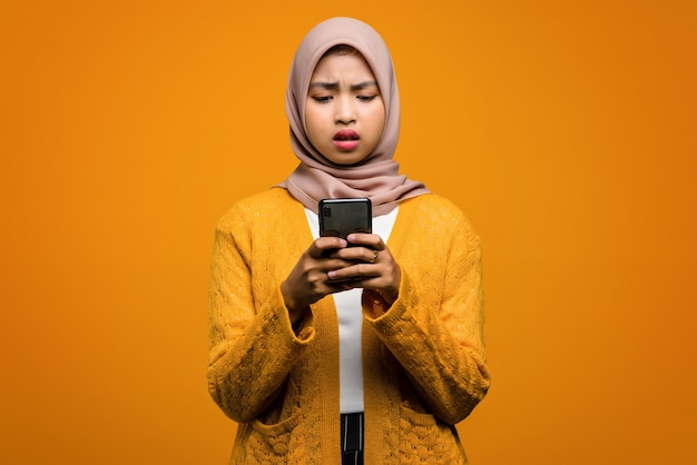 Portrait de la belle femme asiatique à l'aide d'un smartphone avec une expression ennuyée