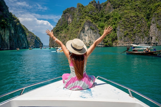Photo portrait d'une belle femme asiatique assise sur un bateau passant par un lac de plage par une journée d'été ensoleillée heureuse femme se détendre et profiter de la vie en plein air en vacances sur l'île tropicale de phi phi en thaïlande