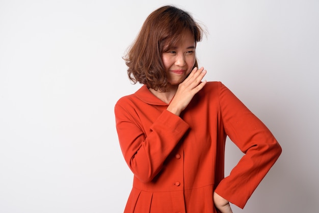 Portrait de la belle femme asiatique aux cheveux courts contre le mur blanc