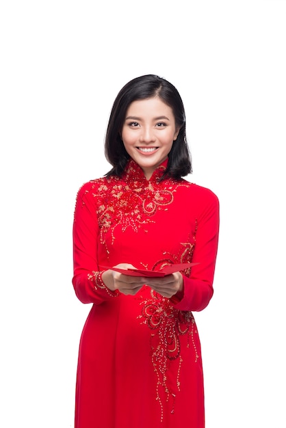 Portrait d'une belle femme asiatique en costume de festival traditionnel Ao Dai tenant une poche rouge - argent chanceux. Vacances du Têt. Nouvelle année lunaire.