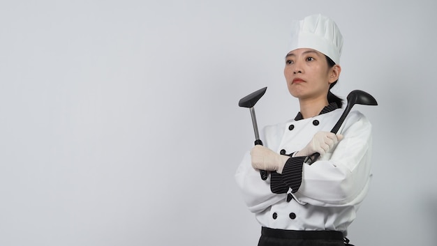 Portrait belle femme asiatique cuisinier portant l'uniforme de chef faisant le geste