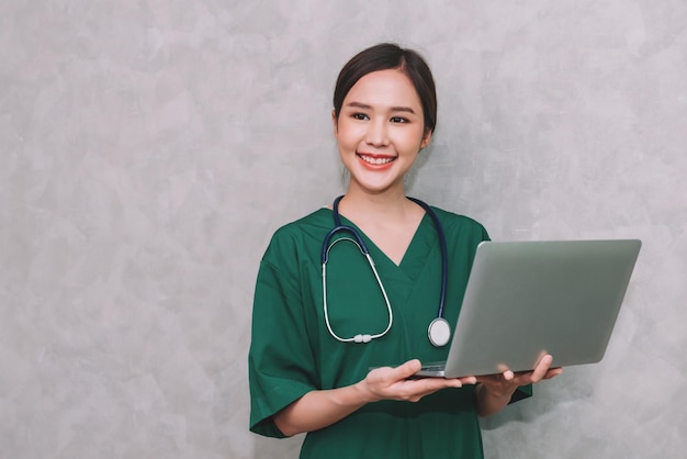 Portrait d'une belle femme asiatique médecin travailleur de la santé à l'aide d'un ordinateur portable isolé sur fond gris