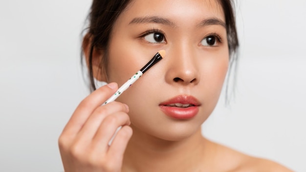 Portrait d'une belle femme asiatique avec un pinceau de maquillage