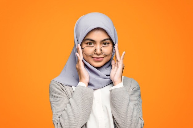 Portrait de la belle femme asiatique portant le hijab et tenant des lunettes