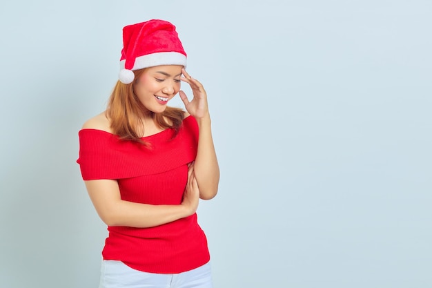 Portrait d'une belle femme asiatique portant une robe de Noël pensant à quelque chose avec le doigt sur la tête sur fond blanc