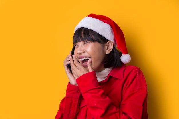 Portrait belle femme asiatique porter le chapeau de Noël du père Noël parler au téléphone