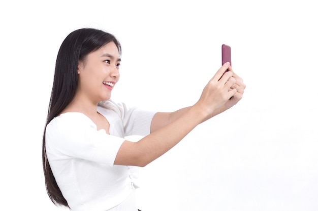 Portrait d'une belle femme asiatique qui a les cheveux longs noirs en chemise blanche tient le smartphone