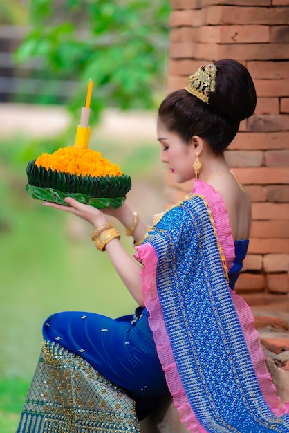 Portrait d'une belle femme asiatique en robe thaïlandaise priant traditionnellement tenir le kratong pour rejoindre le festival loy kratong en thaïlande