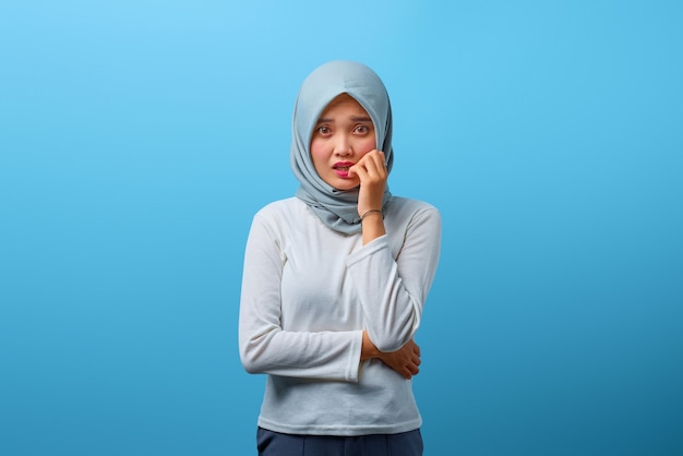 Portrait d'une belle femme asiatique semblant stressée et nerveuse avec la main sur la bouche se ronger les ongles