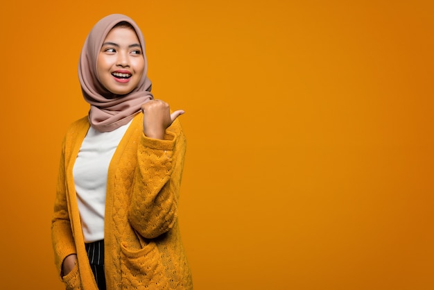 Portrait de la belle femme asiatique souriant et pointant avec le doigt vers un espace vide