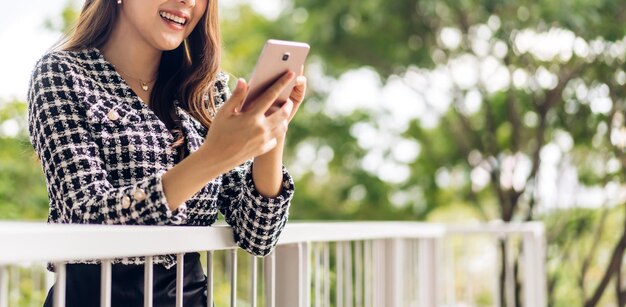 Portrait d'une belle femme asiatique souriante et heureuse se relaxant à l'aide d'un smartphone numérique