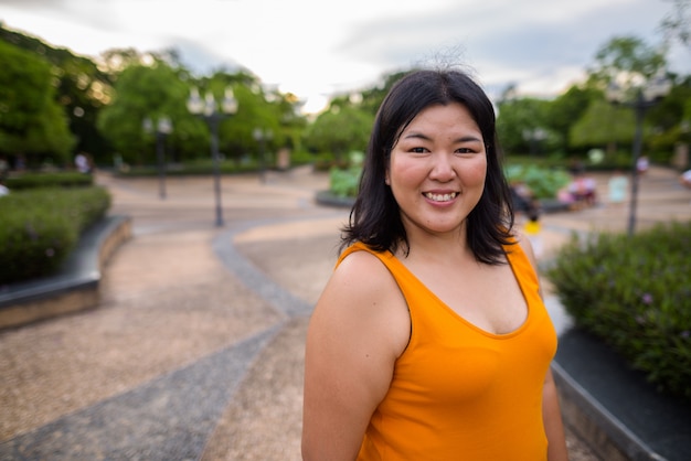 Portrait de la belle femme asiatique en surpoids se détendre dans le parc de la ville de Bangkok, Thaïlande