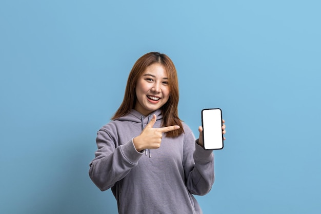 Portrait d'une belle femme asiatique tenant un téléphone portable sur le concept de portrait de fond isolé utilisé pour la publicité et la signalisation isolée sur l'espace de copie de fond bleu