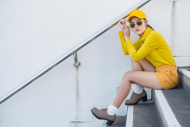 Portrait d'une belle femme asiatique en tissu jauneHipsters fille porter un chapeau jaune dans l'escalier pour prendre une photoThaïlandais dans le style de ton jaune