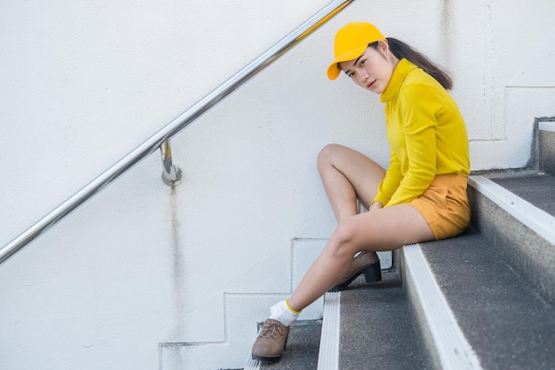 Portrait d'une belle femme asiatique en tissu jauneHipsters fille porter un chapeau jaune s'asseoir sur l'escalier pour prendre une photoThaïlande
