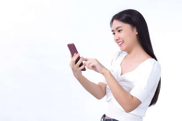 Portrait d'une belle femme asiatique Utilisez le téléphone portable avec plaisir sur un fond blanc.