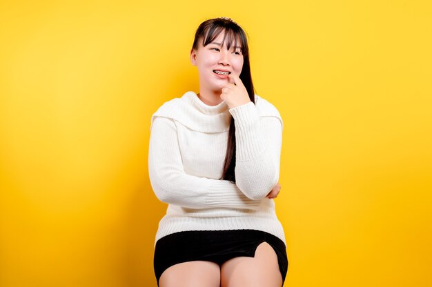 Portrait d'une belle femme asiatique avec un visage souriant. Femme asiatique portant des vêtements décontractés. Mode de vie thaïlandais. jolie fille sourire éclatant sur fond jaune