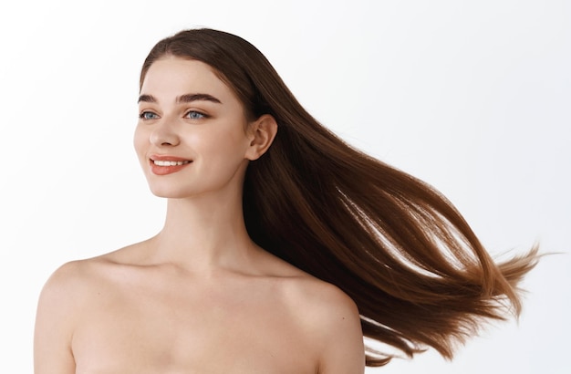 Portrait d'une belle femme aux cheveux longs. Jeune mannequin brune avec de beaux cheveux - isolé sur fond blanc. Jeune fille aux cheveux au vent