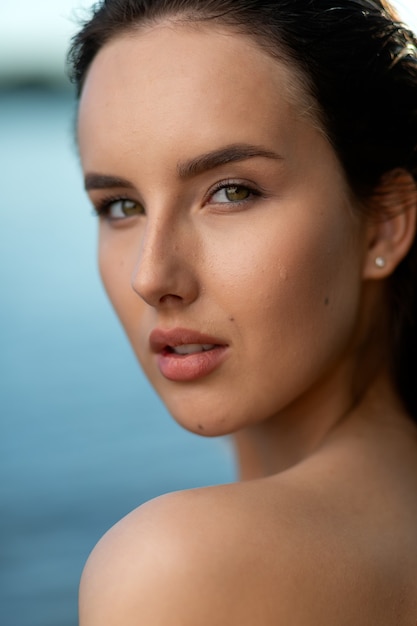 Portrait d'une belle femme aux cheveux mouillés sur fond de mer et de coucher de soleil. jeune femme élégante à la mode sur la plage tropicale