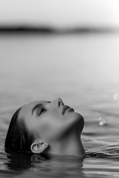 Portrait d'une belle femme aux cheveux mouillés sur fond de mer et coucher de soleil