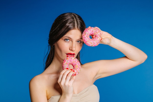 Portrait de belle femme avec beignet isolé sur fond bleu