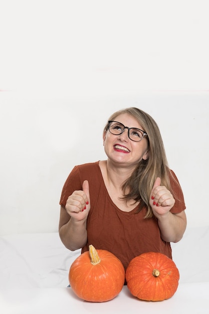 Portrait d'une belle femme blonde d'âge moyen avec citrouille prête pour la maquette de célébration d'halloween pour carte postale et invitation ou publicité