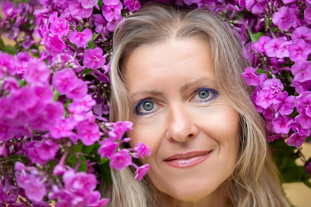 Portrait d'une belle femme blonde d'âge moyen entourée de fleurs violettes