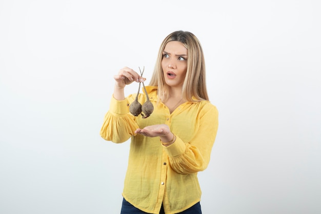 Portrait de la belle femme blonde à la betterave debout sur blanc