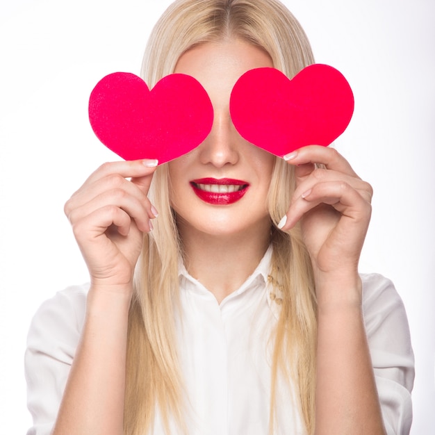 Portrait de la belle femme blonde avec maquillage lumineux et coeur rouge à la main