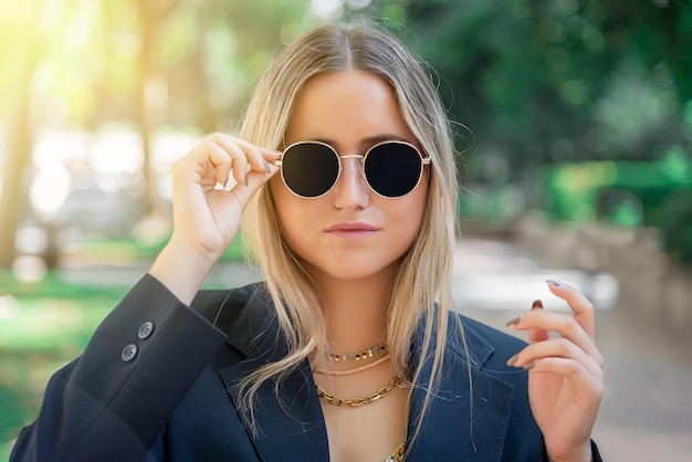 Portrait d'une belle femme blonde mettant des lunettes de soleil