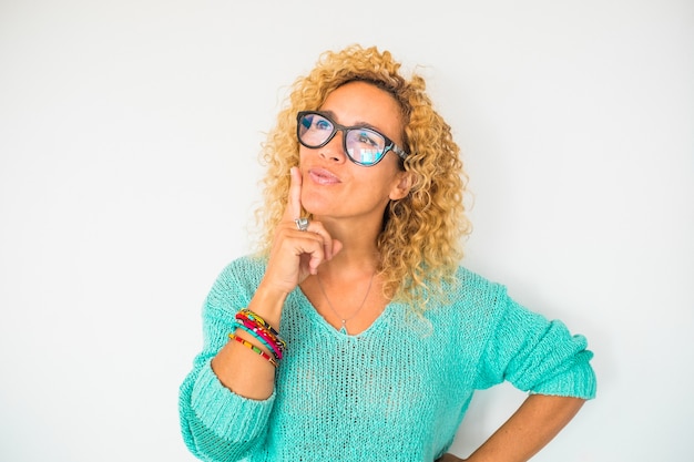 Photo portrait d'une belle femme bouclée pensant et rêvant - gros plan sur des personnes rêveuses portant des lunettes et une chemise bleue sur fond blanc