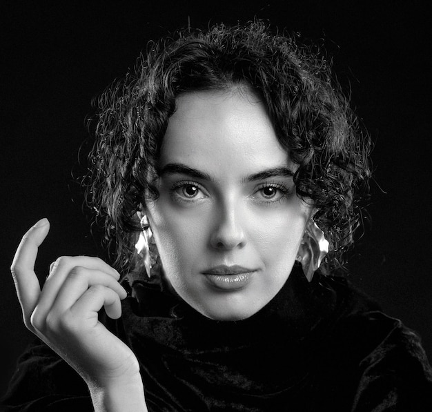 Photo portrait d'une belle femme bouclée posant dans un studio sur un fond noir