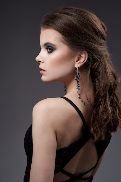 Portrait de belle femme avec boucles d'oreilles et robe noire