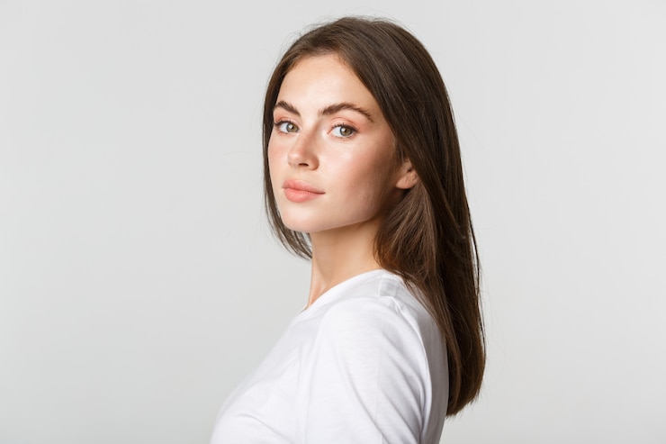 Photo portrait de belle femme brune confiante tournant le visage à la caméra avec un regard rêveur, blanc.