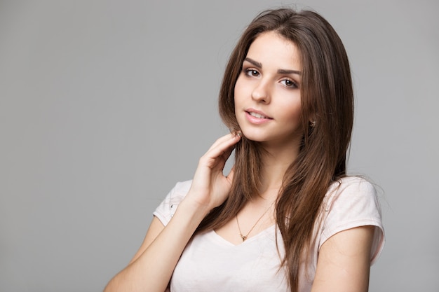 Portrait de belle femme brune avec du maquillage naturel sur fond gris