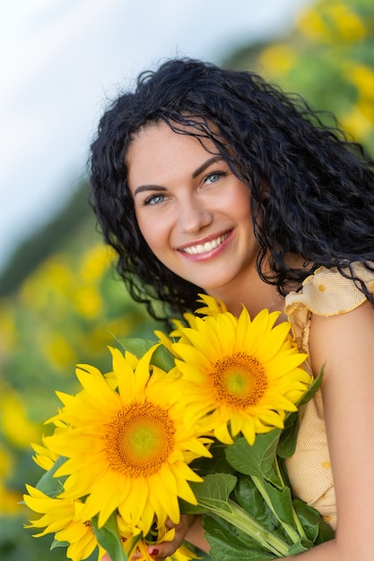 Portrait d'une belle femme brune souriante avec bouquet de tournesols