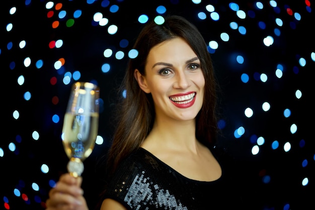 Portrait d'une belle femme buvant du champagne contre un équipement d'éclairage éclairé