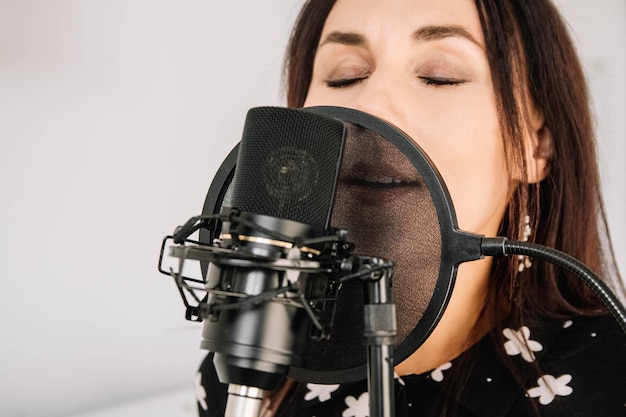 Portrait de belle femme chante une chanson près d'un microphone dans un studio d'enregistrement. visage en gros plan