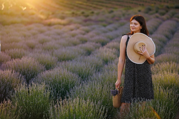 Portrait d'une belle femme avec un chapeau de paille dans un champ de lavande