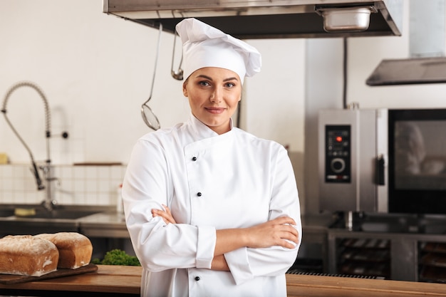Portrait de la belle femme chef vêtu d'un uniforme blanc, posant dans la cuisine au restaurant