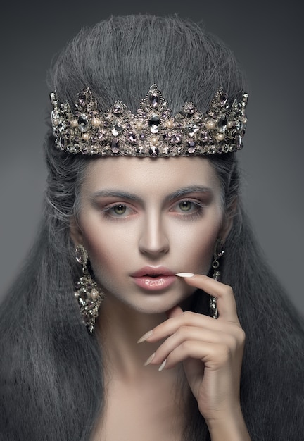 Portrait d'une belle femme à la couronne de diamant et boucles d'oreilles