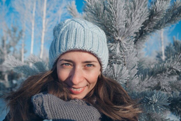 Portrait d'une belle femme dans un chapeau sur la forêt d'hiver