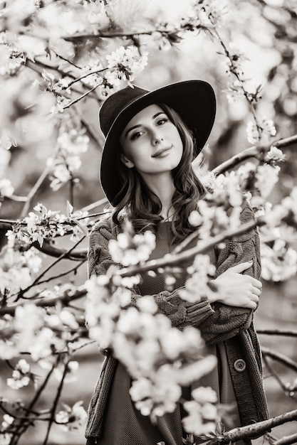 Portrait d'une belle femme dans le jardin de pommiers en fleurs au printemps au coucher du soleil. Image dans le style de couleur noir et blanc