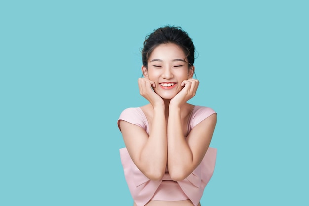 Portrait d'une belle femme drôle levant les paumes près du visage et souriant debout sur fond cyan Concept d'émotions