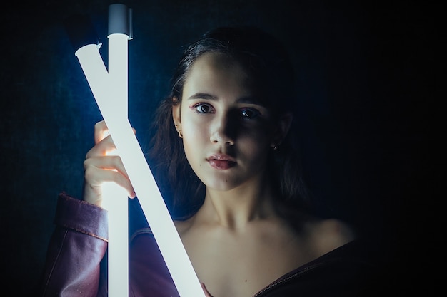 Portrait d'une belle femme élégante avec des épaules ouvertes dans un costume à la mode de veste en cuir rouge posant autour de néons lumineux