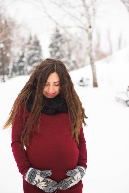 Portrait de la belle femme enceinte dans le parc d'hiver.