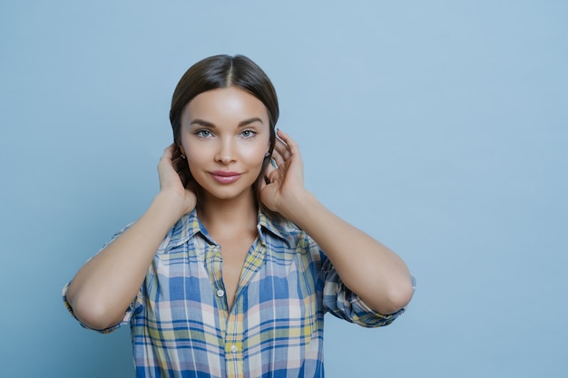 Portrait de la belle femme européenne aux cheveux noirs a une peau éclatante de santé, maquillage, vêtu d'une chemise à carreaux décontractée