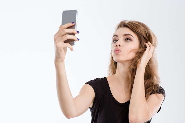 Portrait d'une belle femme faisant selfie photo sur smartphone isolé sur fond blanc
